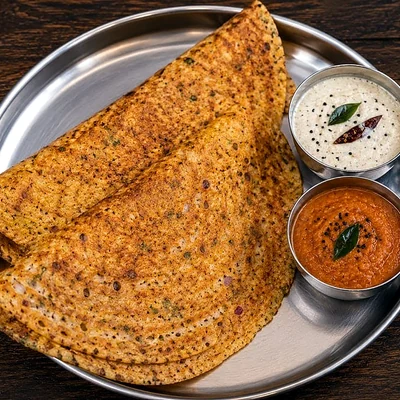 Two golden dosas with coconut chutney and tomato chutney on a steel plate