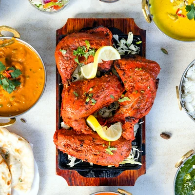 Tandoori chicken platter surrounded by bowls of curry and rice