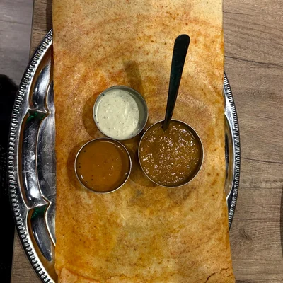 Large dosa with sambar and chutneys on a steel platter