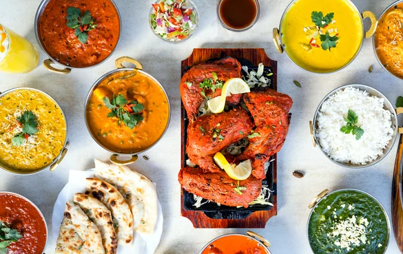Table spread of Indian curries, rice, naan and tandoori